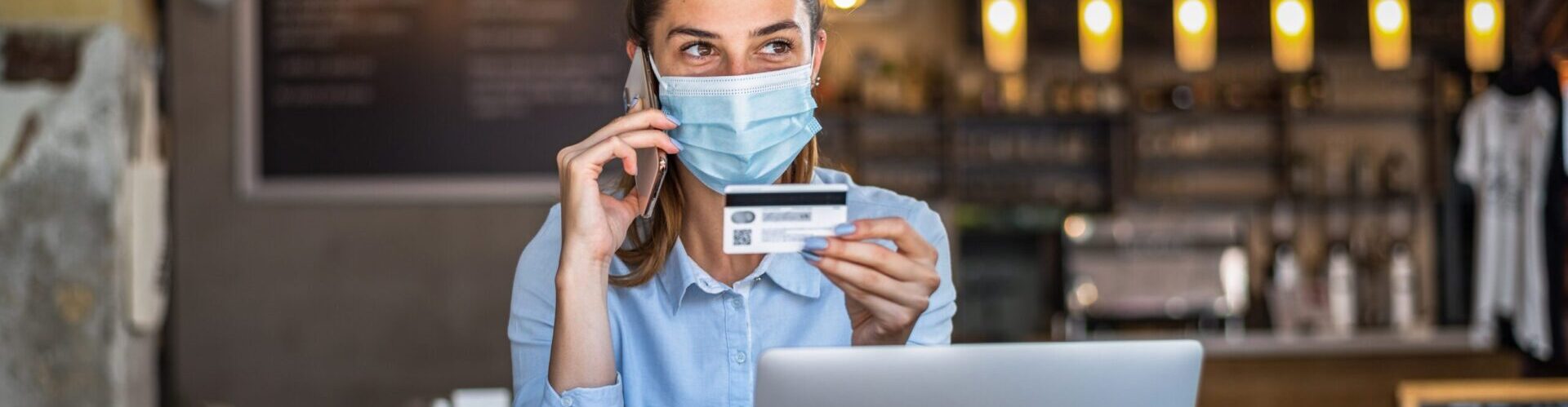 Portrait of young business woman wearing mask while doing shopping online and payment by credit cards. Conceptual of new normal lifestyle during covid-19 pandemic.