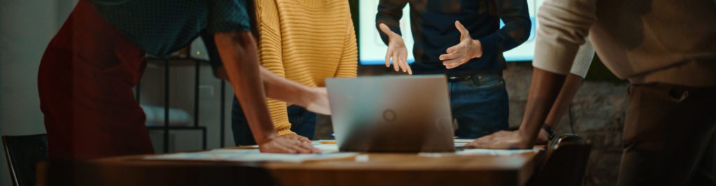 Team having a conversation at work with desk and laptop.
