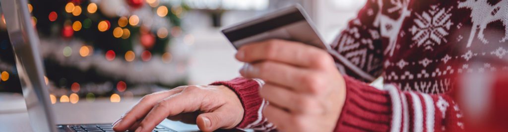 Women wearing red sweater shopping online and using credit card at home office.