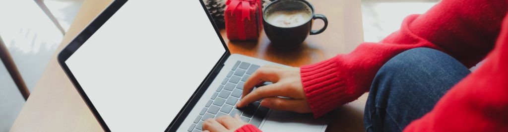 Woman in red sweater typing on laptop.