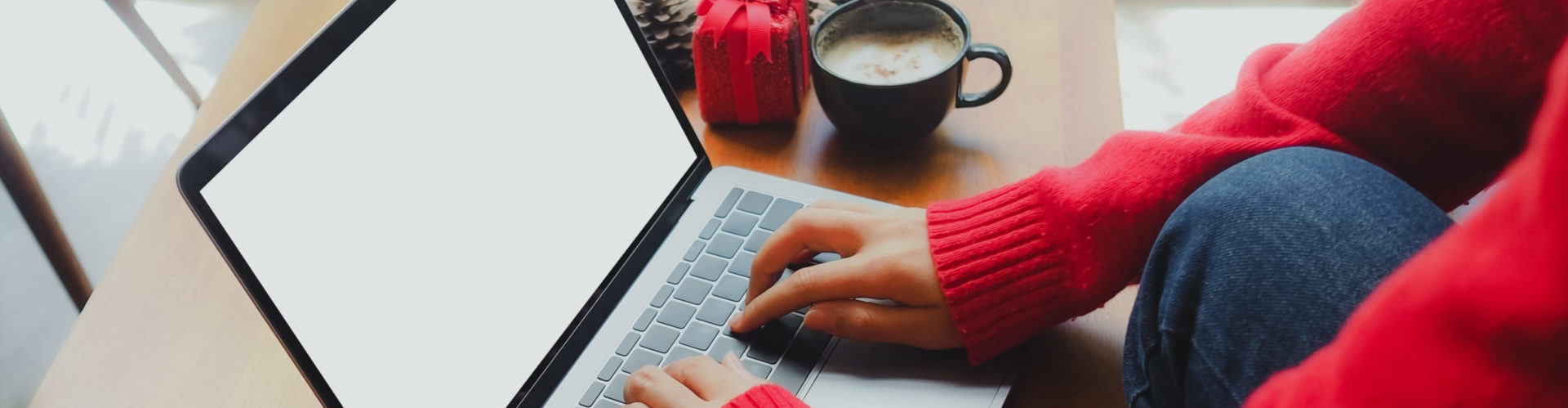 2022 holiday ecommerce strategy - person in sweater shopping on computer with holiday items nearby