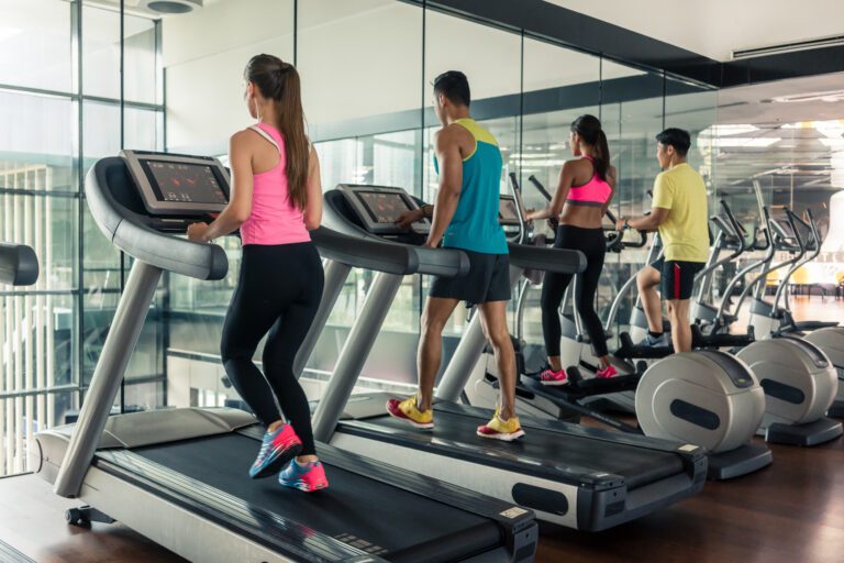 Active woman running on treadmill during high-intensity cardio session in a trendy fitness club with modern equipment.