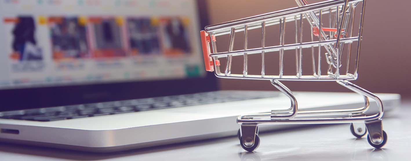 Small shopping cart on a desk next to a laptop.