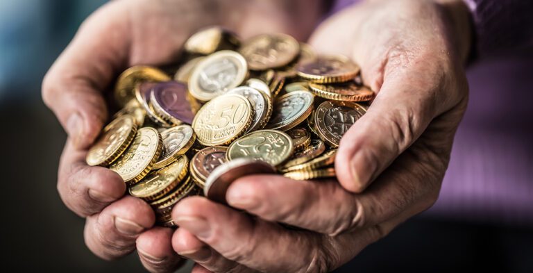 Two hands cupped together holding large pile of collectible coins.