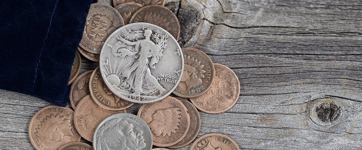 Collectible coins spill out of velvet bag onto wooden tabletop.