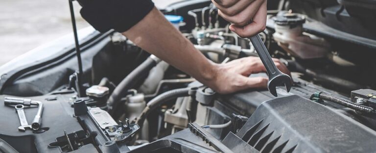 Person with a wrench making repairs to their car.
