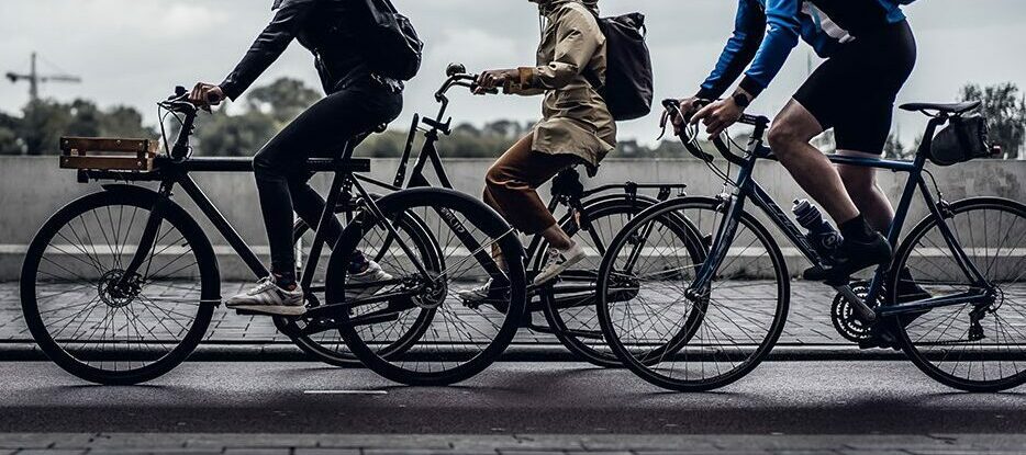 Three cyclists riding bikes on street.