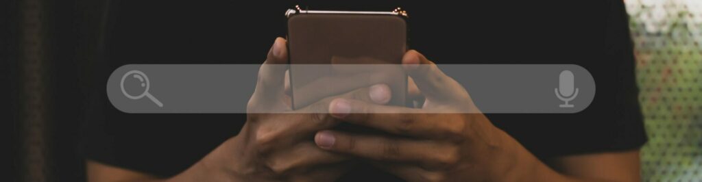 Young asian man wearing black t-shirt sitting on desk hand holding smartphone to Searching for information. Using Search Console with your website.