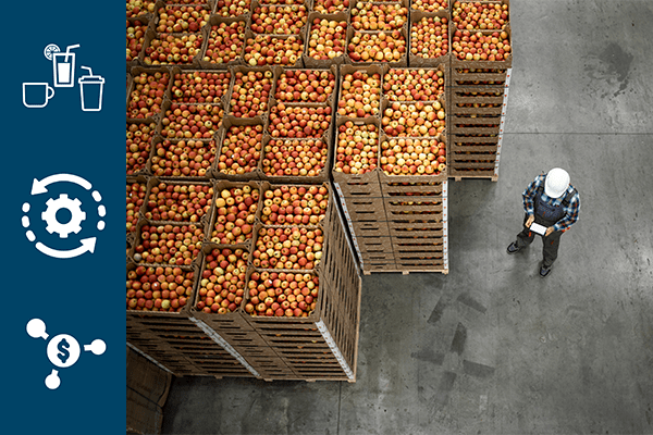 Many crates of apples with person wearing a hardhat in a warehouse.