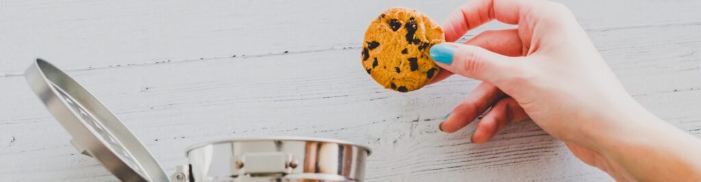 hand throwing cookie into a trash can, metaphor about website cookies and user tracking technologies