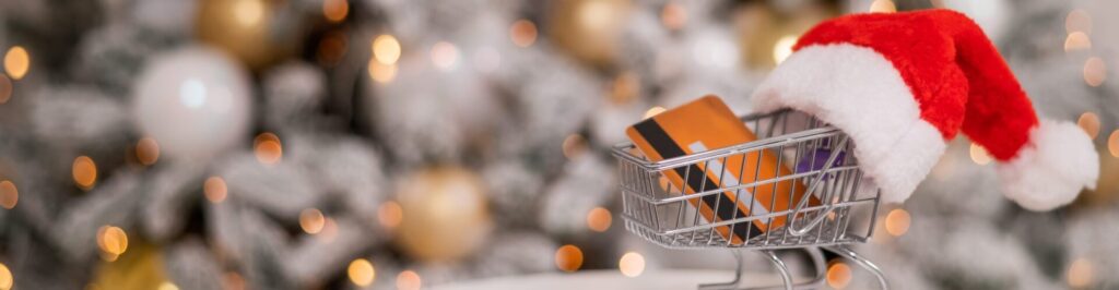 Christmas gifts shopping concept. Credit card in the shopping cart by the christmas tree