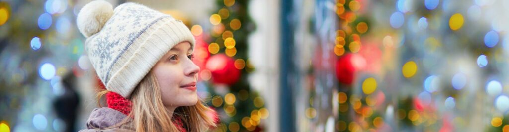 Girl on a Parisian street or at Christmas market looking at shop windows decorated for Christmas