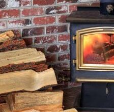 Stack of chopped wood in front of wood burning stove.