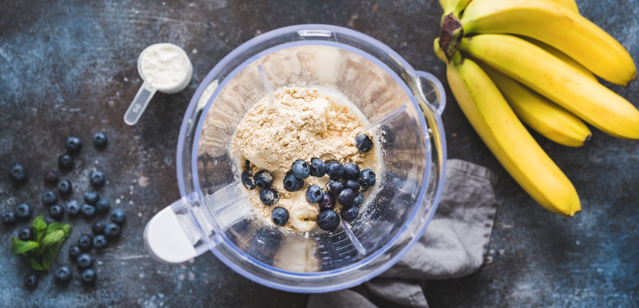 Blueberry protein powder in blender, smoothie preparation, top view. Concept of fitness healthy eating, clean eating, sport lifestyle.