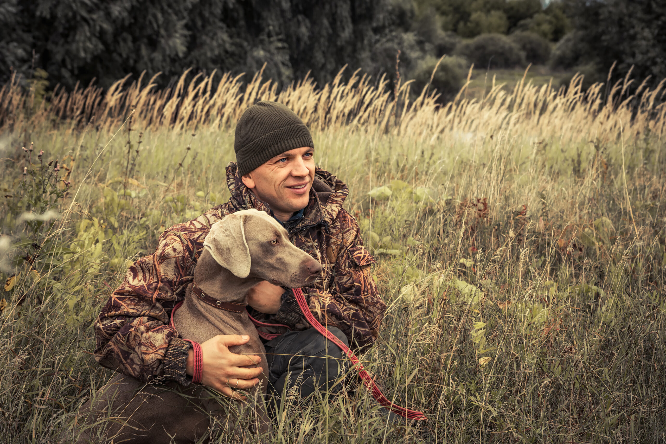 Male hunter in tall grass with dog.