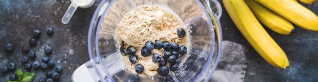 Blueberry protein powder in blender, smoothie preparation, top view. Concept of fitness healthy eating, clean eating, sport lifestyle.