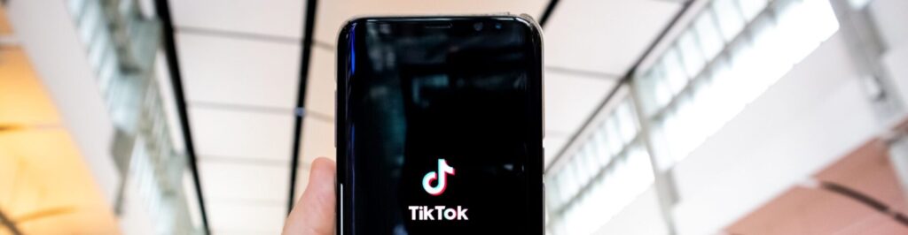Person holding phone with TikTok on screen in a shopping mall.