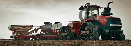 Large farming tractor in field planting crops