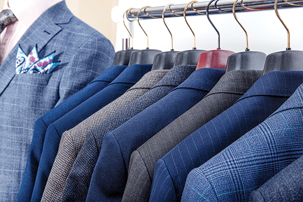 Men's suit jackets hanging on a clothing rack.