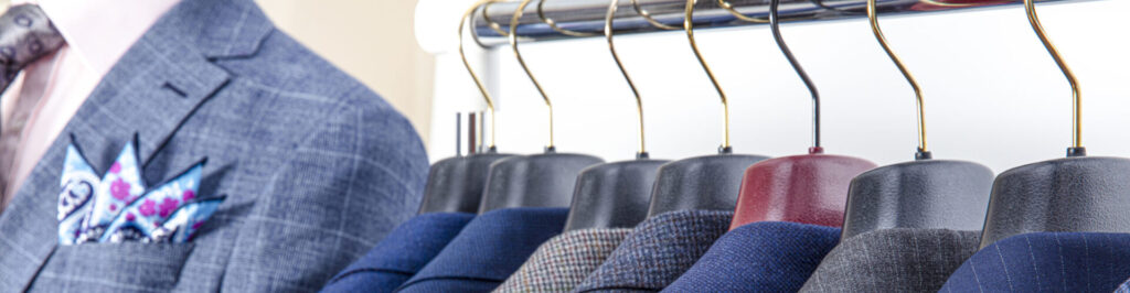 Men's suit jackets hanging on a clothing rack.