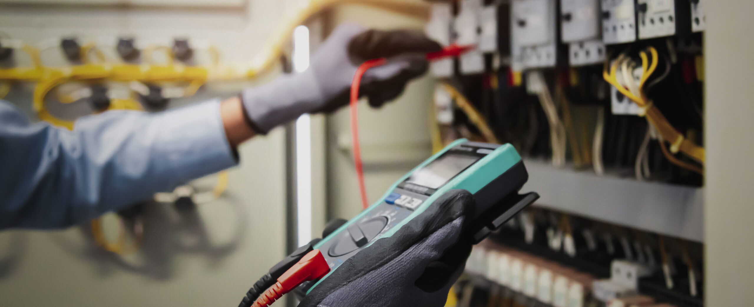 Electricity and electrical maintenance service, Engineer hand holding AC multimeter checking electric current voltage at circuit breaker terminal and cable wiring main power distribution board.