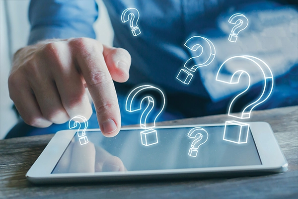 Person typing on tablet with animated question marks popping out of it.