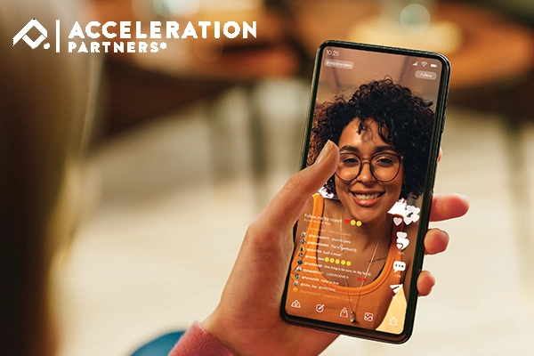 Person watching TikTok on phone; photo has overlay of Accleration Partners logo.