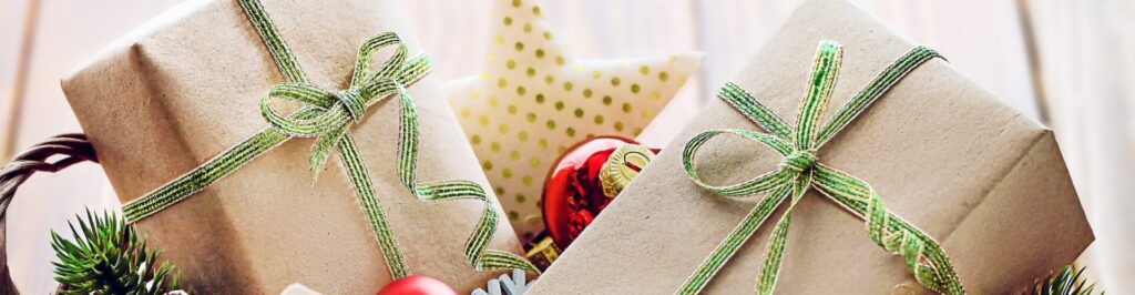 Basket with holiday items like pinecones, candy canes, ornaments, bows, and wrapped presents.