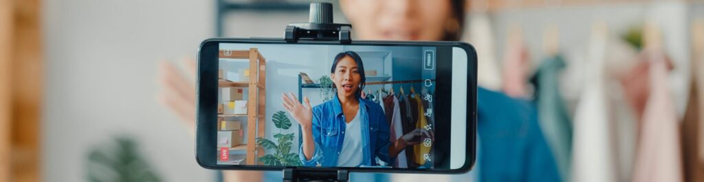 Influencer wearing jean jacket recording a video on her phone.