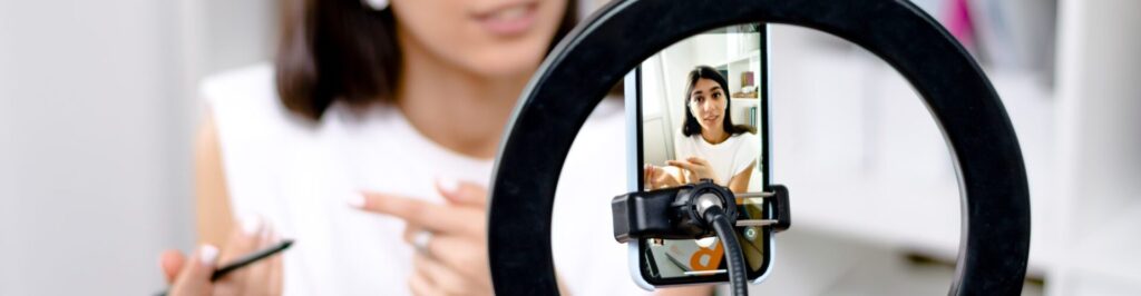 Influencer girl blogger talking smartphone,live recording video blog on social network at home.Social media live streaming concept.Focus on the phone, the girl in the background in a blur.