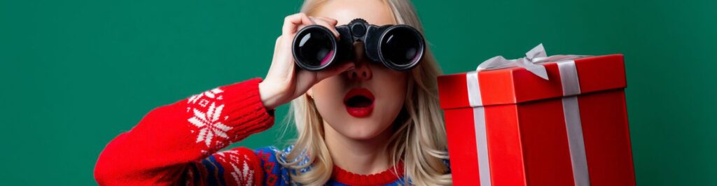 Woman in holiday sweater holding gift and binoculars.