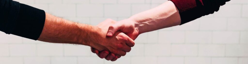 Men shaking hands wearing long sleeve shirts.