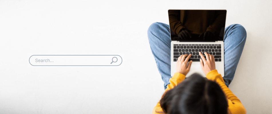 Hands typing on laptop with search bar on the left side
