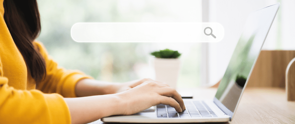 woman typing on laptop with search bar hovering above computer