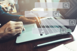 marketer typing seo tips on laptop with search bars floating above