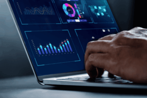 Close up of hands typing on a laptop. Screen shows illuminated performance data
