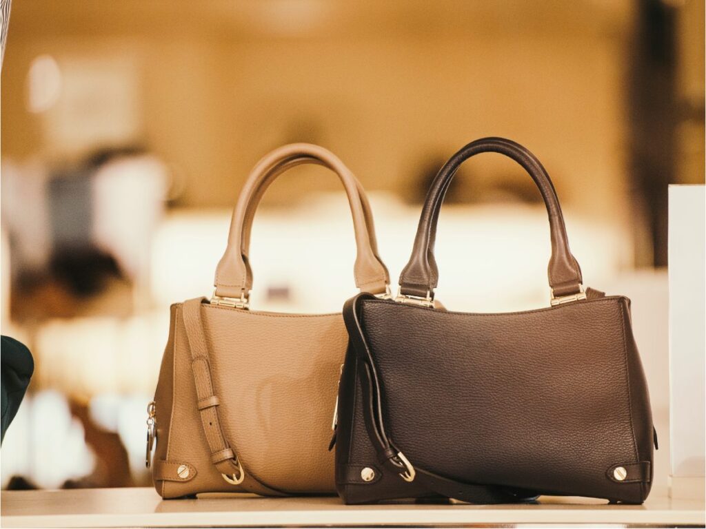 Tan and dark brown leather handbags displayed on a boutique shelf”